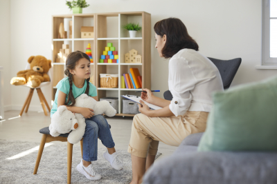 little girl sharing her concerns with supportive child psychologist during therapy session