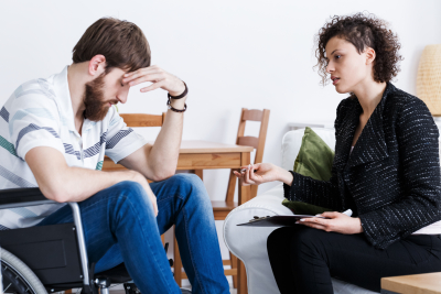 woman counseling a sad man in a wheelchair